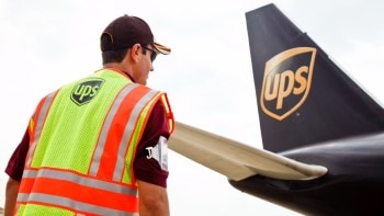 UPS employee in vest next to tail of UPS plane